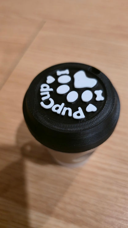 Close-up of black lid with raised white paw print and PupCup text
