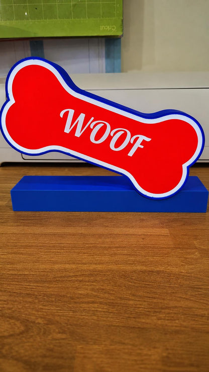 Red dog bone light box with white outline on a freestanding base